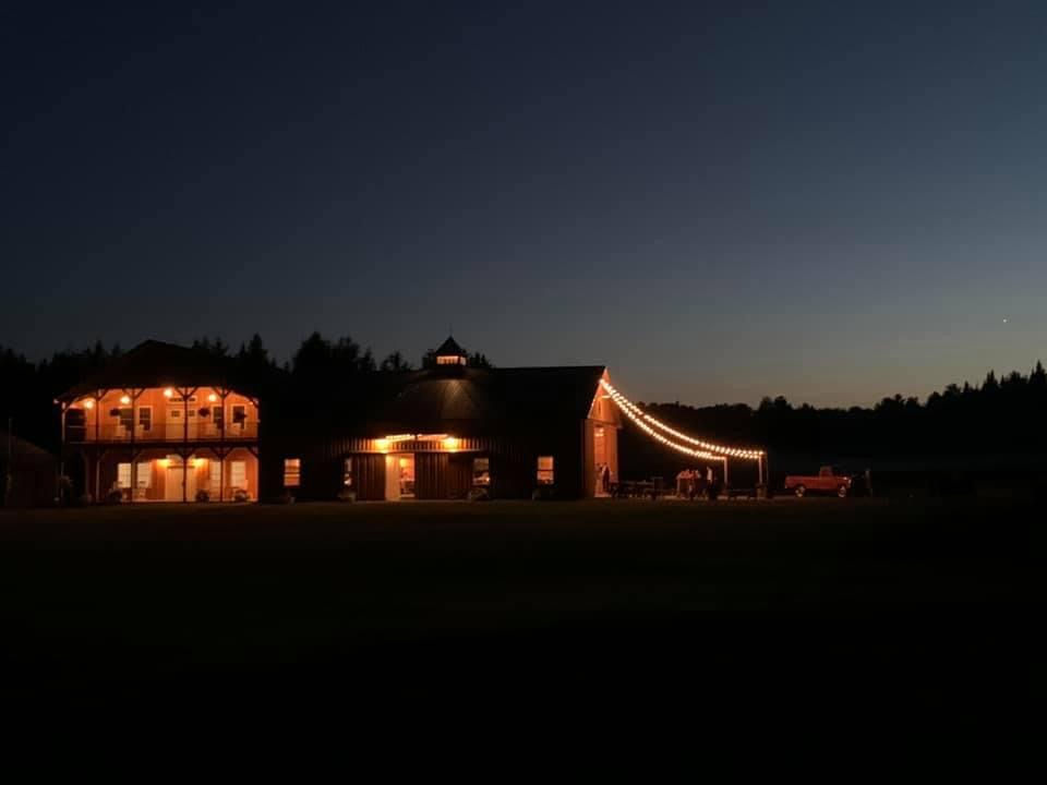 The Sunset Meadows barn complex lit with string lights at night